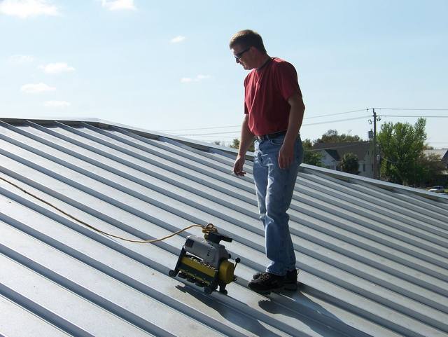 Roofer operating a seaming machine to join standing-seam metal roof panels