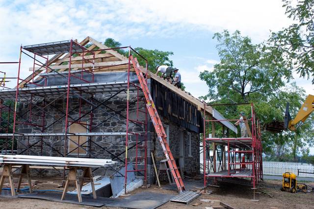 Roofing crew installing new wood shingles on a roof during a restoration project