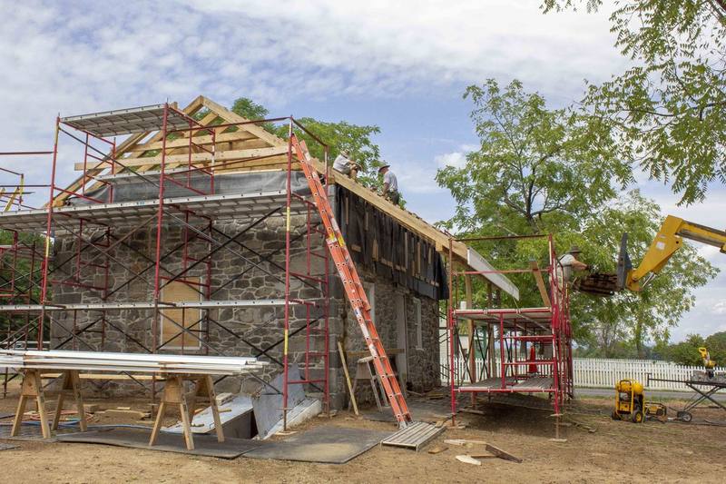 Local roofers pausing while installing new wood shingles on a roof during restoration work