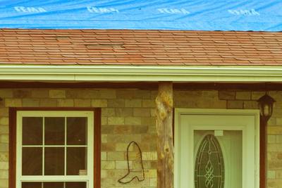 Blue tarp secured over a tornado-damaged home's roof
