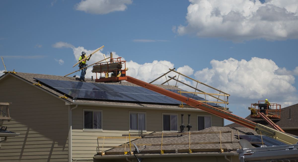Crew installing new asphalt shingles across a full residential roof replacement