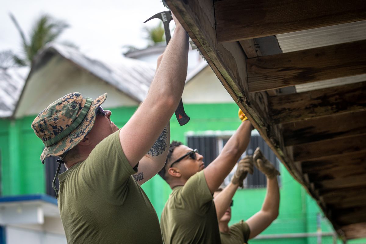 Service member installing a fascia board as part of a rain gutter installation project