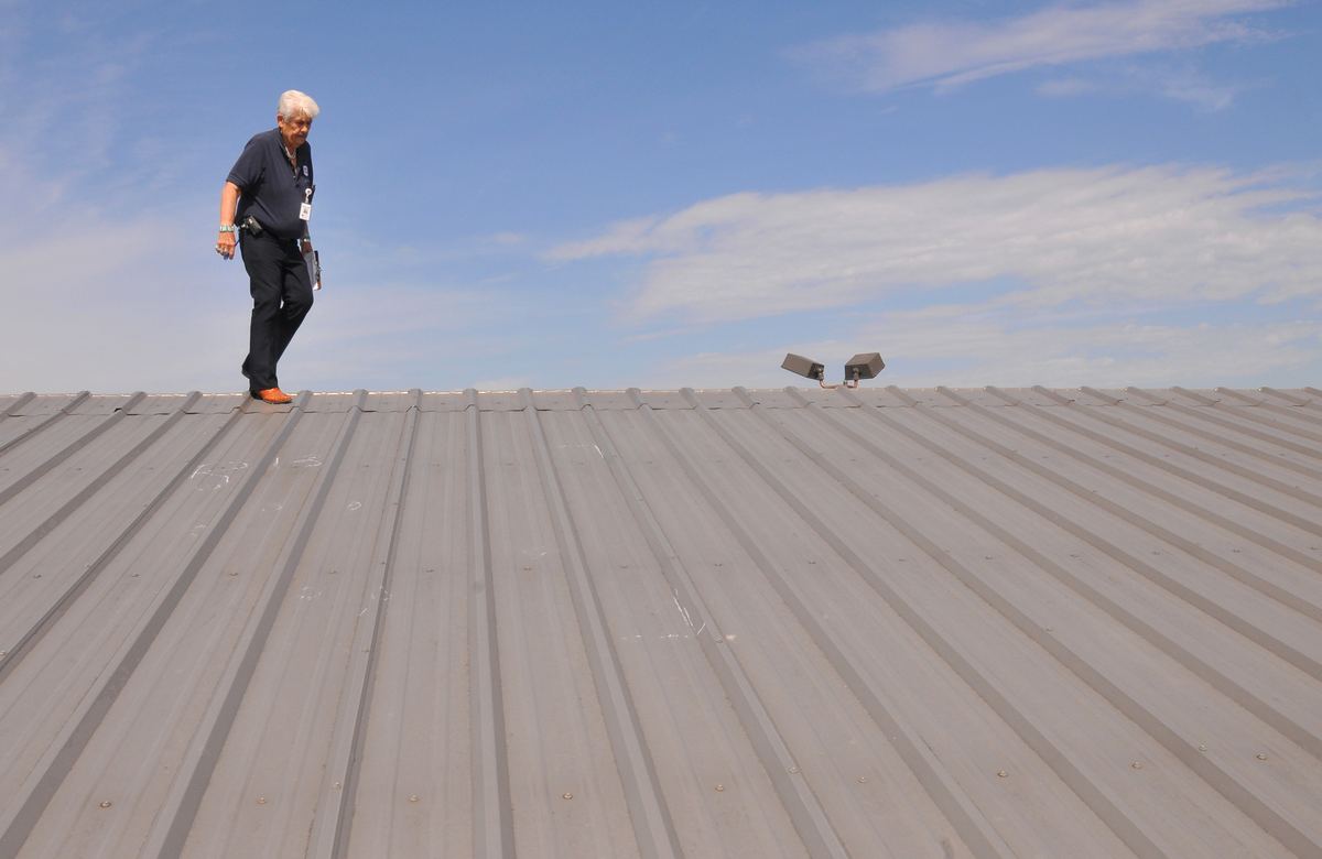 Inspector examining hail-damaged shingles during a roof damage assessment