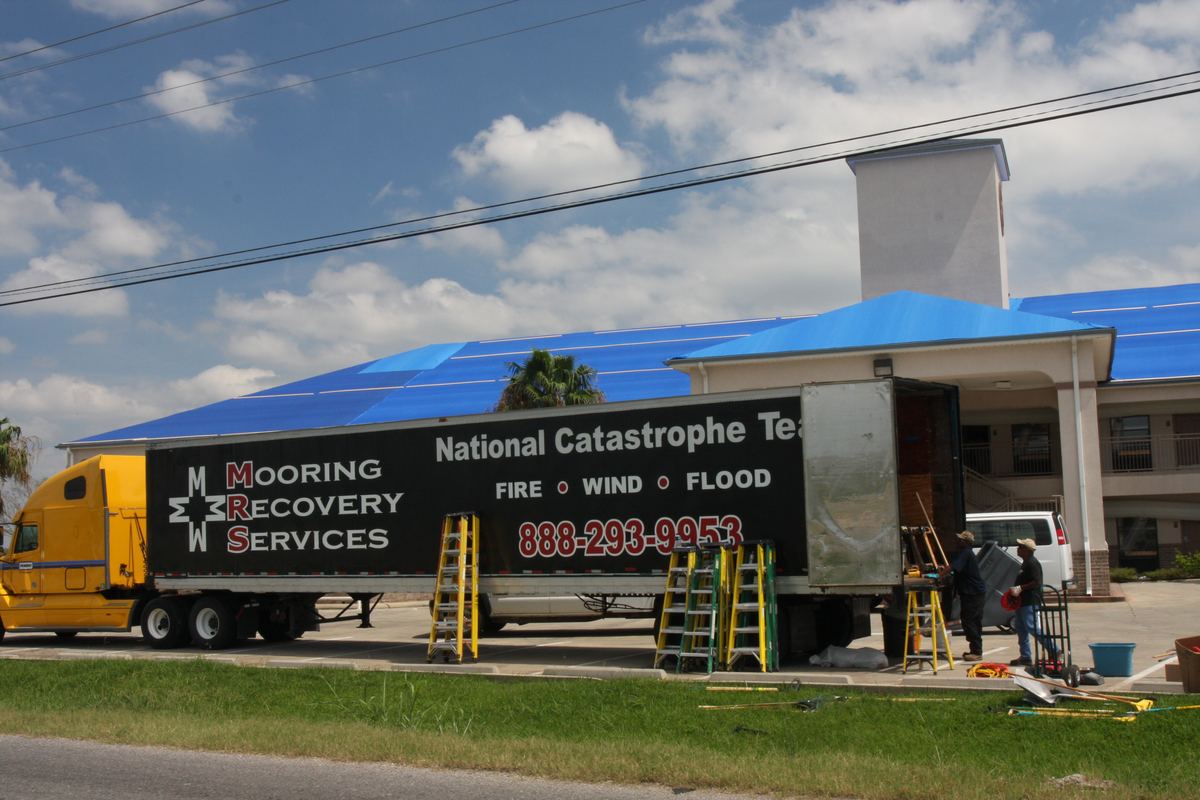 Blue tarp covering storm-damaged roof sections on a building
